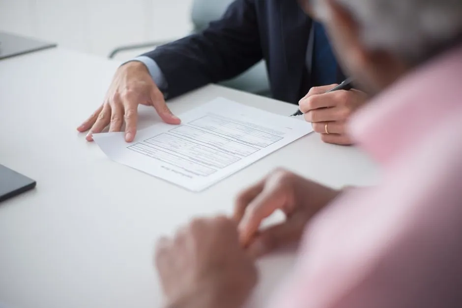 Close-up of a person signing a printed document with a pen, illustrating finalizing a business contract